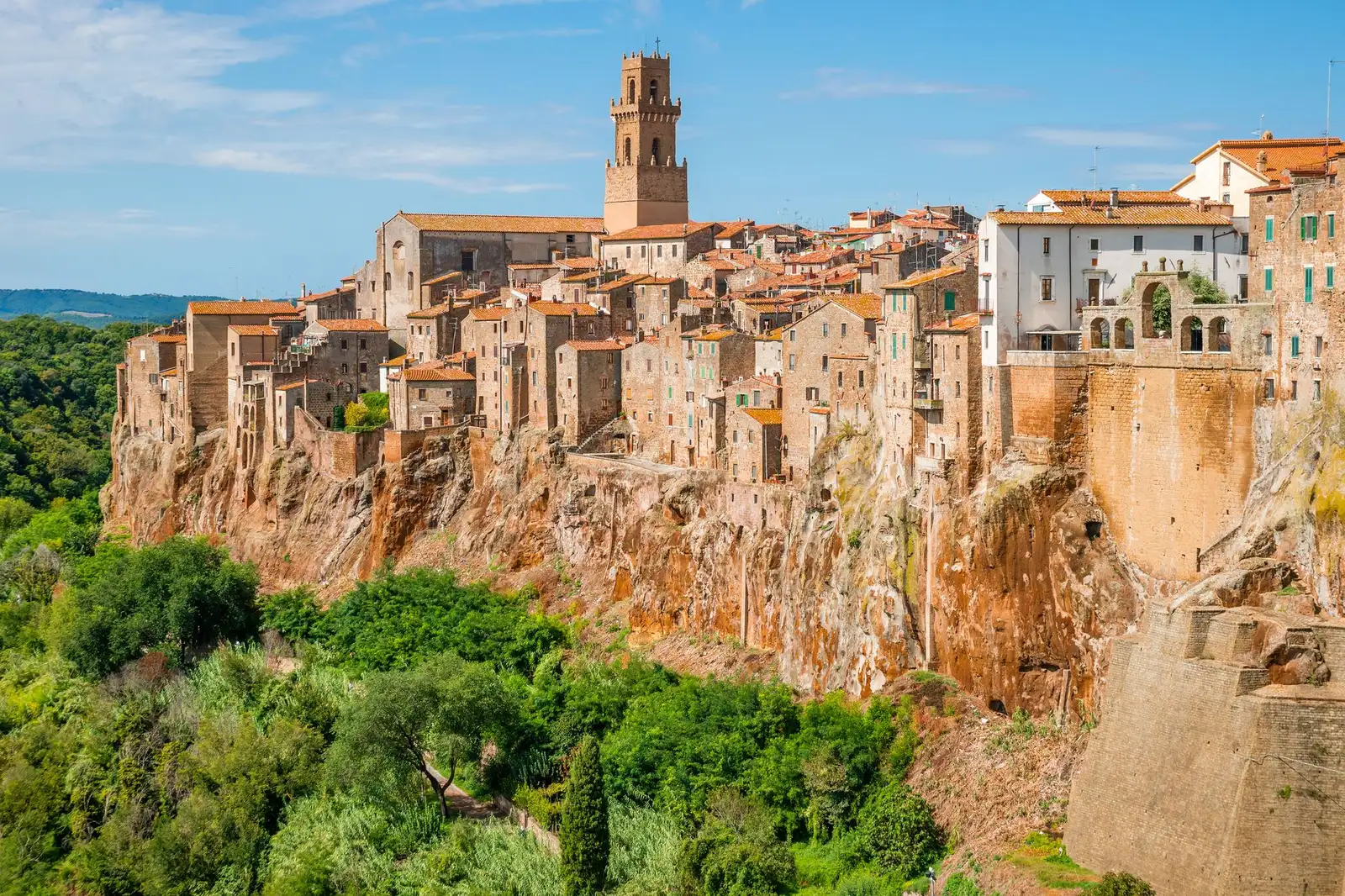 Discover the charming medieval town of Pitigliano set atop Tuscany's cliffs under a bright sky.