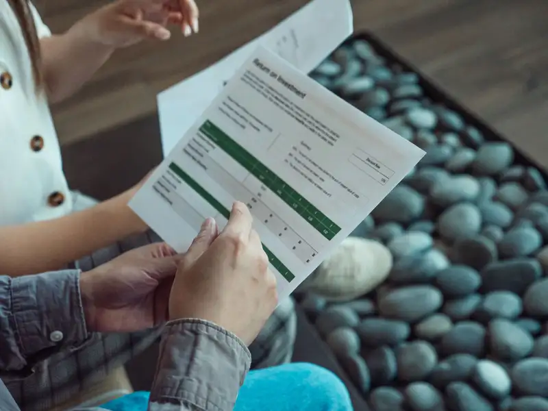 Two people discussing a financial document showing return on investment data.
